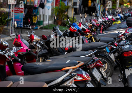 KRABI, THAILAND - 10. Juli 2019. Üblichen überfüllten Parkplatz in Krabi, mit voller Motorräder. Eine Menge Motorräder parken in Zeilen im Bürgersteig in Stockfoto