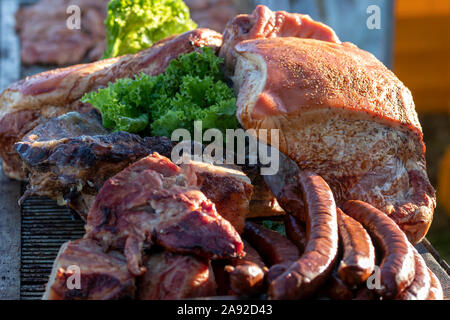 Ein Haufen gegrillte und geräucherte Fleisch- und Wurstwaren in einer Garküche. Nahrung fest Veranstaltung, Sommer Tag. Stockfoto