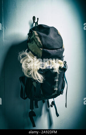 Blonde Perücke Auslaufen aus einem Rucksack. Stockfoto