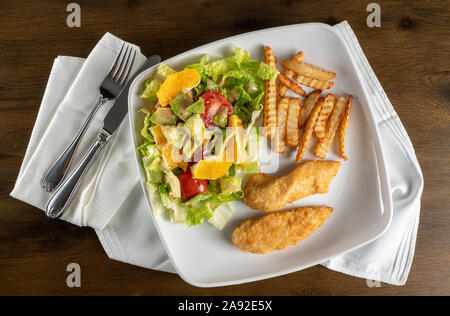 Von oben Blick auf hausgemachten Salat, Pommes und Chicken Nuggets vergoldet Angebote oder zu Hause mit Serviette Stockfoto