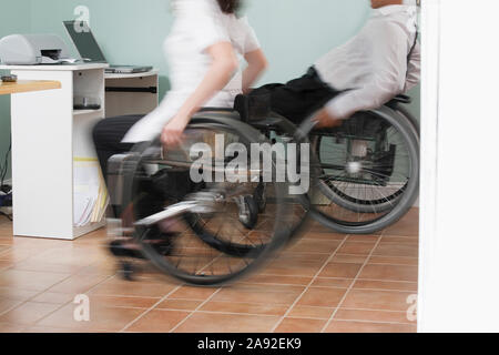 Mann und Frau sitzen im Rollstuhl mit einem Spinal Kabelverletzungen im Home Office Stockfoto