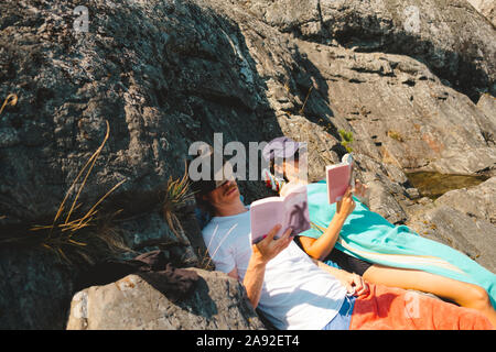 Mann und Frau lesen Bücher auf Felsen Stockfoto