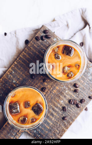 Kaffee Espresso mit Milch Eiswürfel im Glas auf weißem Hintergrund. Kalten Sommer Getränke. Ansicht von oben. Stockfoto