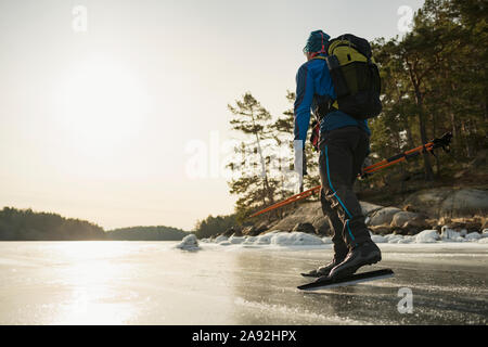 Mann, Schlittschuhlaufen auf dem zugefrorenen See Stockfoto