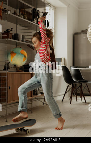 Mädchen auf Skateboard zu Hause Stockfoto