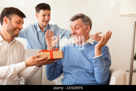 Sohn und Enkel gratulieren älterer Mann saß auf der Couch Indoor Stockfoto