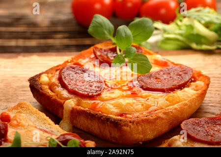 Geröstetes Brot mit Käse, Wurst und Kräuter Stockfoto