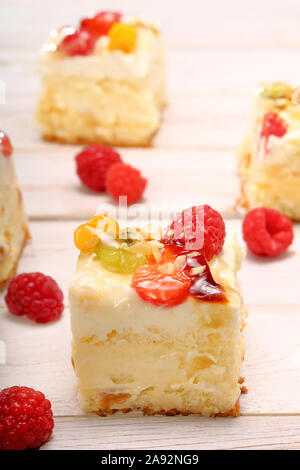 Cremige Kuchen mit Früchten auf hölzernen Hintergrund und leeren Raum für Text Stockfoto