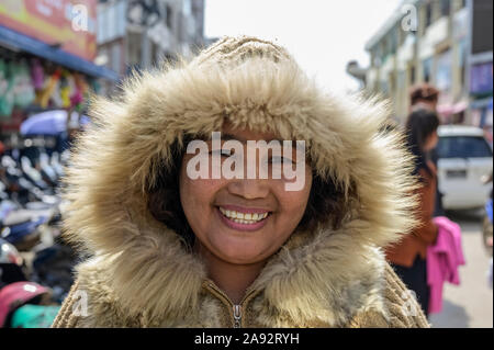 Frau in einem warmen, mit Pelz beschnittenen Mantel auf dem Markt; Lashio, Shan State, Myanmar Stockfoto