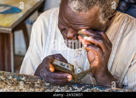 Sudanesischer Mann, der ein Mobiltelefon repariert; Kerma, Nordstaat, Sudan Stockfoto