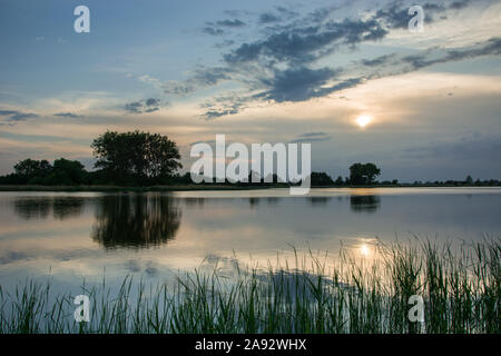 Sonne hinter den Wolken über den See und Bäume Stockfoto