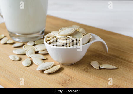 Close-up, Kürbiskerne und Glas Kürbis Milch auf Holz- Hintergrund Stockfoto