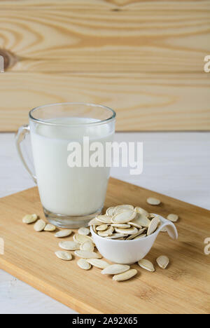 Close-up, Kürbiskerne und Glas Kürbis Milch auf Holz- Hintergrund Stockfoto