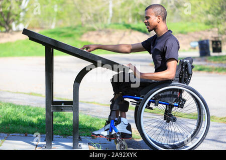 Mann, der eine Spinale Meningitis in einem Rollstuhl hatte und einen las parkverzeichnis Stockfoto