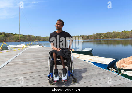 Mann, der eine Spinalmeningitis in einem Rollstuhl hatte, auf dem er saß Ein Dock Stockfoto