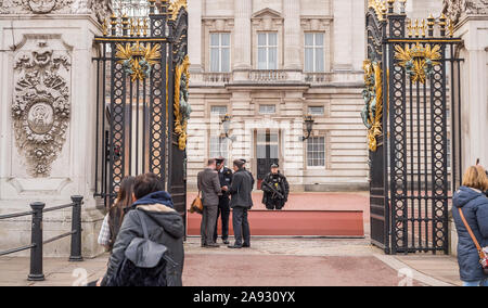 Blick durch die offenen Tore des Buckingham Palace, im Zentrum von London, Großbritannien. Bewaffnete Polizei auf der Wache, die die Sicherheit der Besucher überprüft. Königliche Familie bewachen. Stockfoto