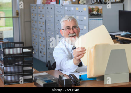 Mann mit Muskeldystrophie in einem Rollstuhl Unterlagen in Sein Büro Stockfoto