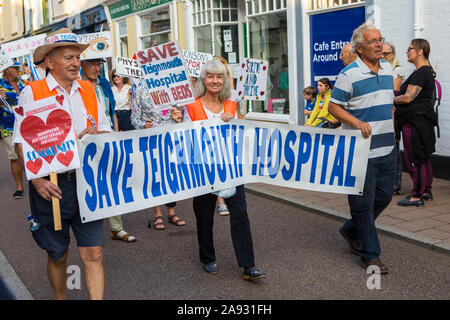 Devon, UK - 1. August 2019: Mitglieder der Gemeinschaft im Badeort Teignmouth, Devon, mit einem Speichern Teignmouth Krankenhaus Fahne während des Stockfoto