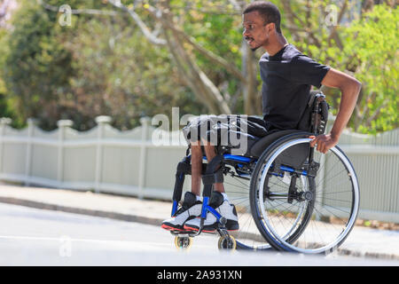 Mann in einem Rollstuhl, der Spinale Meningitis hatte, die die überquerte Straße Stockfoto