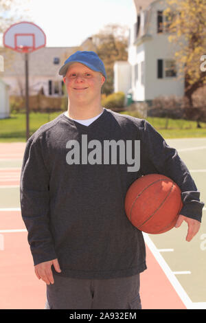 Porträt eines jungen Mannes mit Down-Syndrom hält Basketball Im Park Stockfoto