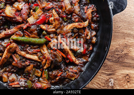 Pfannengerichte Gemüse und Fleisch aus Gusseisen Pfanne mit Sojasauce und Gewürzen flach auf einem Tisch Stockfoto