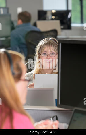 Junge Frau mit Down-Syndrom arbeitet an ihrem Computer in Ein Büro Stockfoto