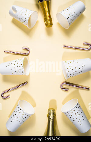 Neues Jahr Partei Thema konzeptionelle Bild, Blick von oben auf die Flache layout Zusammensetzung von Papier Glas mit goldener Dekoration, Zuckerstangen, und goldenen Flaschen von c Stockfoto