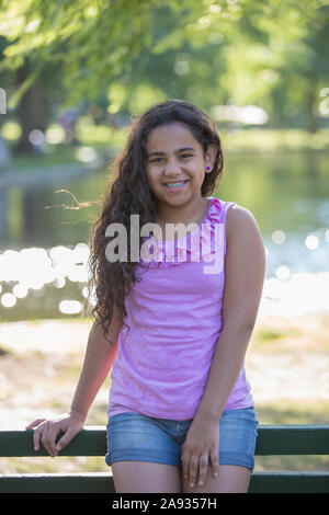 Portrait von Happy Hispanic Teenager-Mädchen mit Zahnspangen sitzen in Der Park Stockfoto
