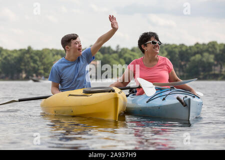 Junger Mann mit Down-Syndrom Kajakfahren mit seinem Freund in Ein See Stockfoto