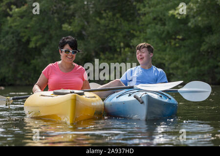 Junger Mann mit Down-Syndrom Kajakfahren mit seinem Freund in Ein See Stockfoto