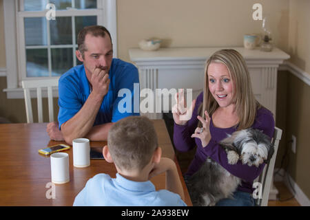 Familie mit Hörbehinderung, sagt in amerikanischer Gebärdensprache "Basketball" mit einem Hund zu Hause Stockfoto