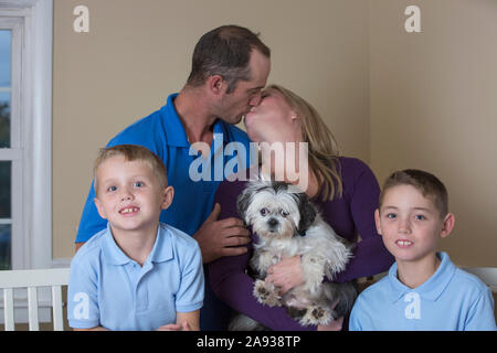 Porträt einer glücklichen Familie mit Hörbehinderungen mit küssenden Eltern Stockfoto