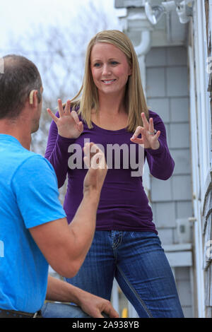 Hausbesitzer kommunizieren mit Hausreparateur in American Sign Language, sagen "New" und "Perfect" Stockfoto