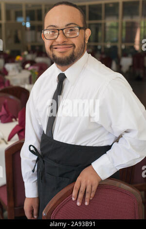 Porträt des afroamerikanischen Mannes mit Down-Syndrom als Kellner im Restaurant Stockfoto