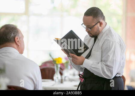 Afroamerikanischer Mann mit Down-Syndrom als Kellner Bestellung vom Kunden im Restaurant Stockfoto