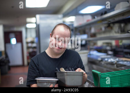 Kellner mit Down-Syndrom arbeitet in der Küche eines Restaurant Stockfoto