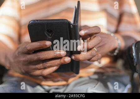 Mann mit Guillain-Barre-Syndrom Textnachrichten auf seinem Telefon Stockfoto