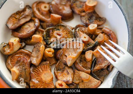 Gebratene Fichte Milch Cap Pilze in der Pfanne auf dem hölzernen Tisch, Nahaufnahme, Ansicht von oben. Stockfoto