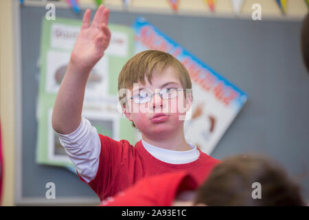 Junge mit Down-Syndrom Heben Hand in einer Schule Klassenzimmer Stockfoto