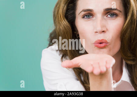 Porträt einer Mitte erwachsenen Frau bläst einen Kuss Stockfoto