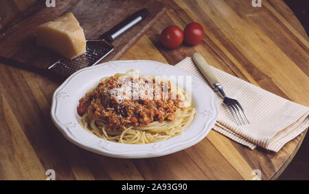 Pasta Bolognese (Spaghetti Bolognese) und Parmesan auf einer weißen Platte. Die klassische italienische Spaghetti auf alten Holz- Hintergrund. Stockfoto