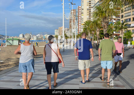 Ältere Ehepaare von hinten, zu Fuß an der Strandpromenade von Playa Levante Strand, Benidorm, Alicante, Spanien Stockfoto