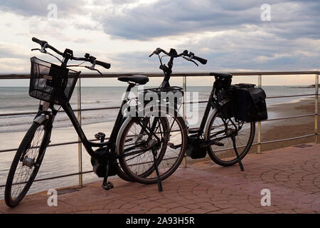 Ein Paar Fahrräder parkten zusammen vor einem Küstenblick Stockfoto