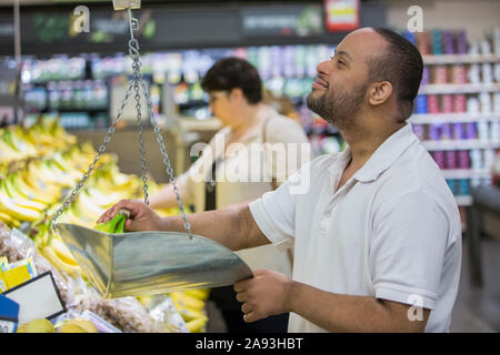 Mann mit Down-Syndrom wiegt Banane in einem Lebensmittelgeschäft Stockfoto