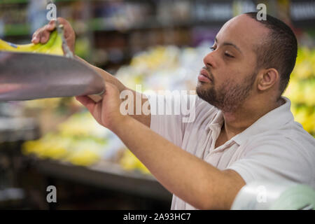 Mann mit Down-Syndrom Gewicht Obst in einem Lebensmittelgeschäft Stockfoto
