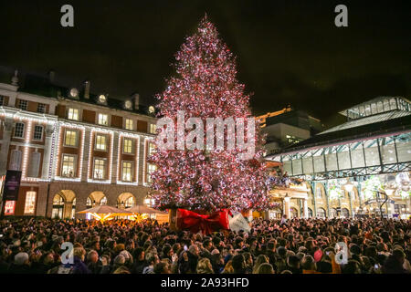 West End, London, Großbritannien, 12. November 2019. Die beleuchteten großen Weihnachtsbaum in Covent Garden Piazza. Zuschauer verfolgen die jährliche Bühnenperformance und Schalter auf der schönen Covent Garden Weihnachtsbaum und Leuchten im Londoner West End. Credit: Imageplotter/Alamy leben Nachrichten Stockfoto