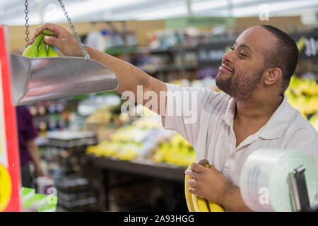 Mann mit Down-Syndrom Gewicht Obst in einem Lebensmittelgeschäft Stockfoto