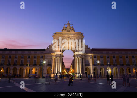 Das 18. Jahrhundert Arco da Rua Augusta (Triumphbogen Gateway) und Touristen am Praça do Comercio Platz im Viertel Baixa in Lissabon, Portugal, in der Dämmerung. Stockfoto