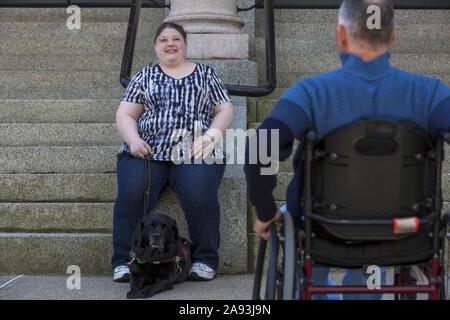 Mann mit Rückenmarksverletzung sitzt im Rollstuhl mit seinem Tochter im Hintergrund, die blind ist Stockfoto