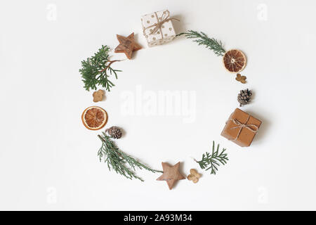 Weihnachten Kreis florale Komposition. Kranz von Juniperus Äste, Tannenzapfen, Geschenkboxen, Holz- Sterne und trockenen orange Frucht auf weißem Hintergrund Stockfoto